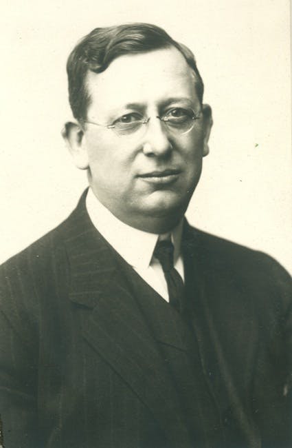 a man wearing a suit and tie smiling at the camera