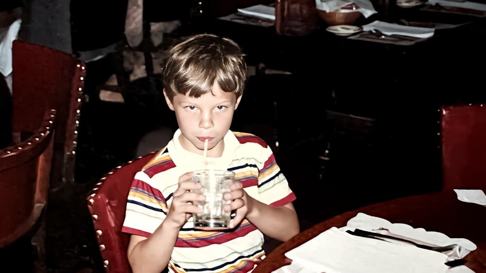a young boy drinking from a glass