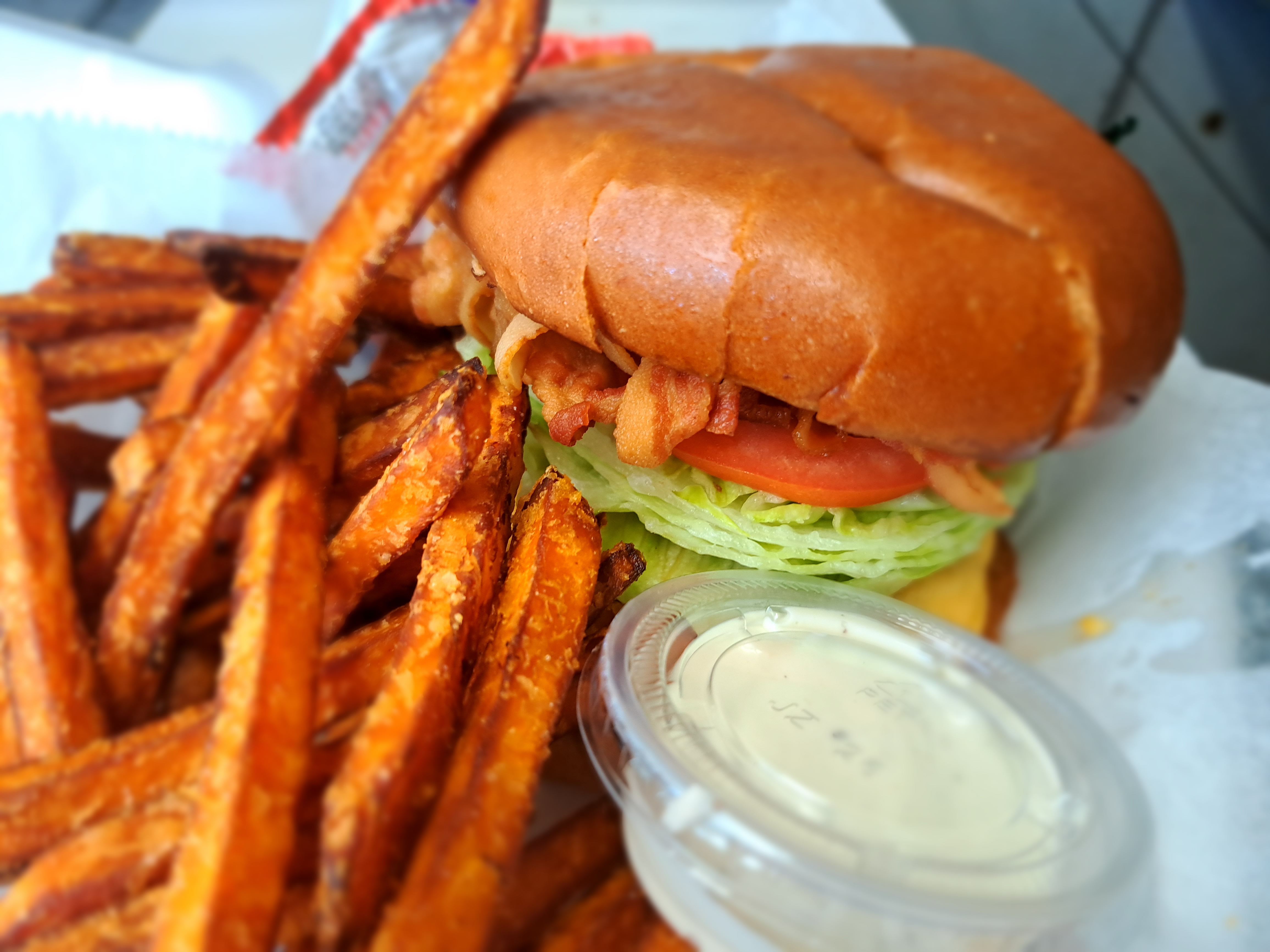 BACON CHEESE BURGERS AND SWEET POTATO FIRES sandwich sitting on top of a pile of fries