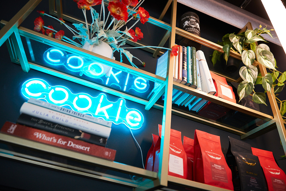 a shelf with books and a neon sign