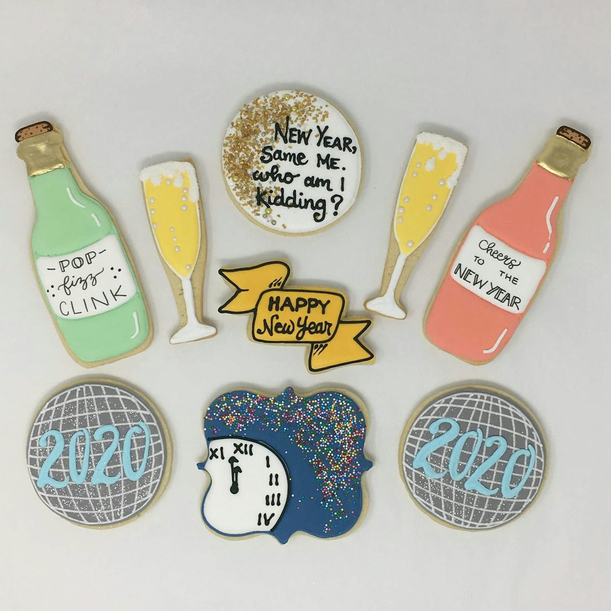 a group of new years themed cookies - champagne bottle, champagne flute, banner, clock, new year's ball
