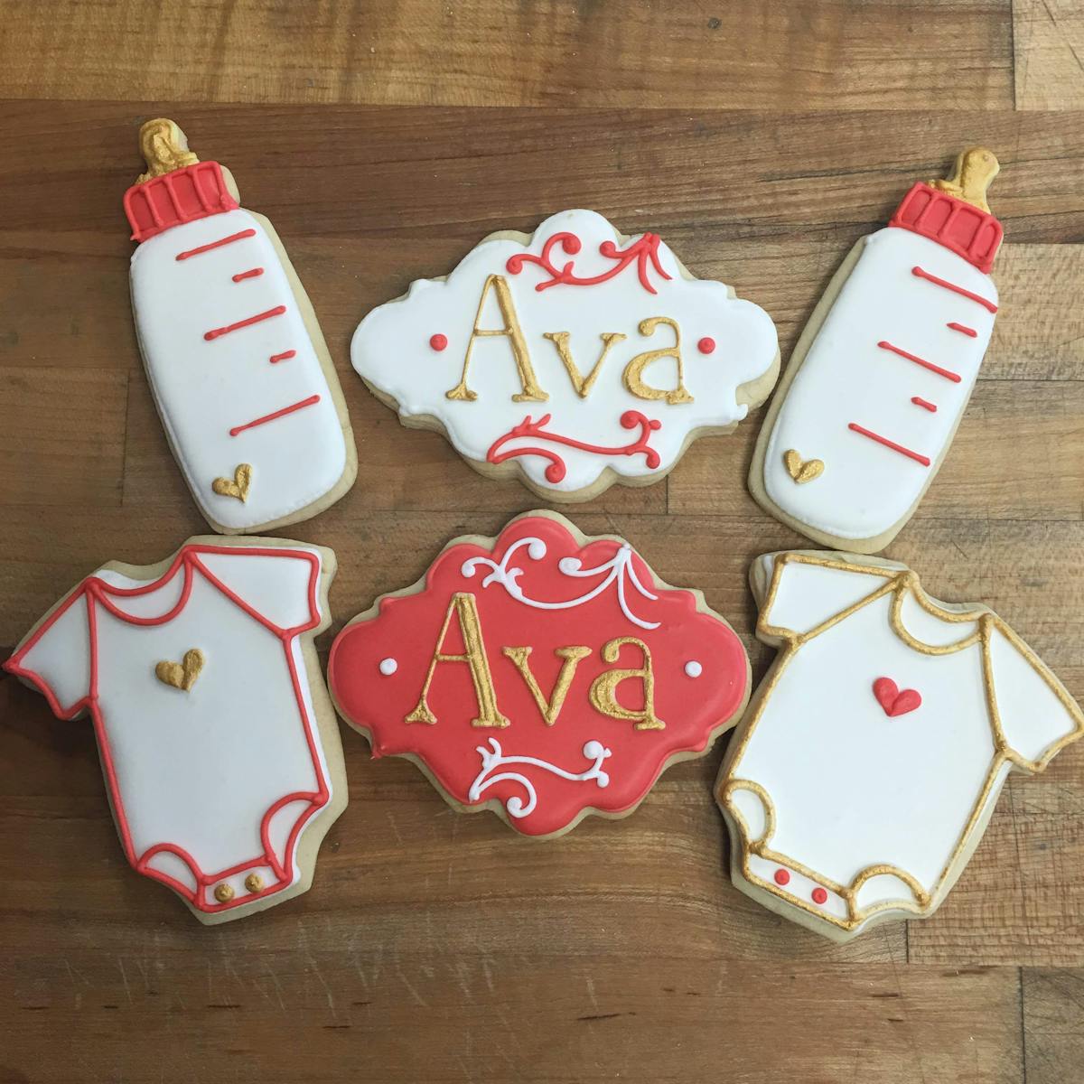 baby shower cookies of bottles, onesies, and name plaques