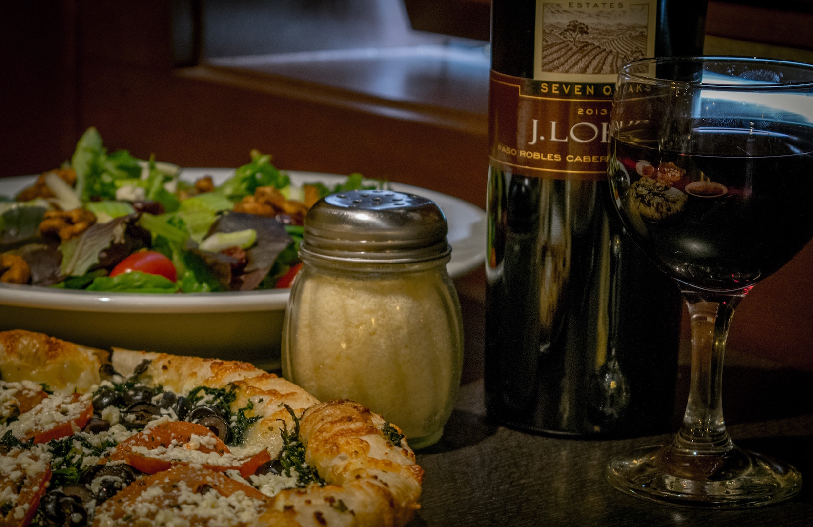 a pizza sitting on top of a table next to a glass of wine