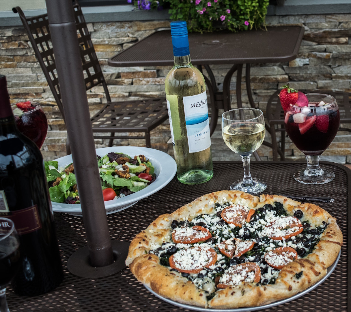 a pizza sitting on top of a table next to a glass of wine