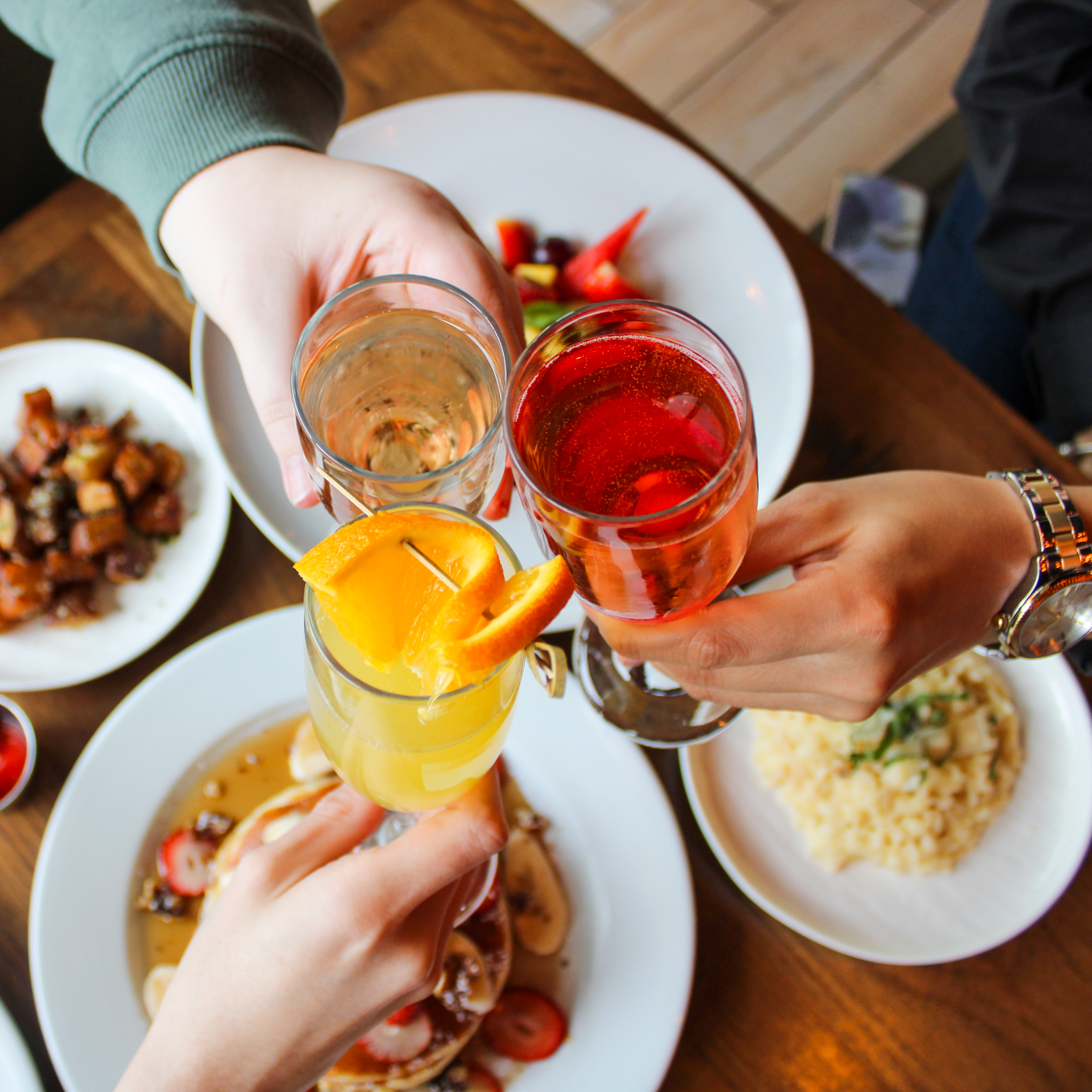 A group of people toasting their drinks at table.