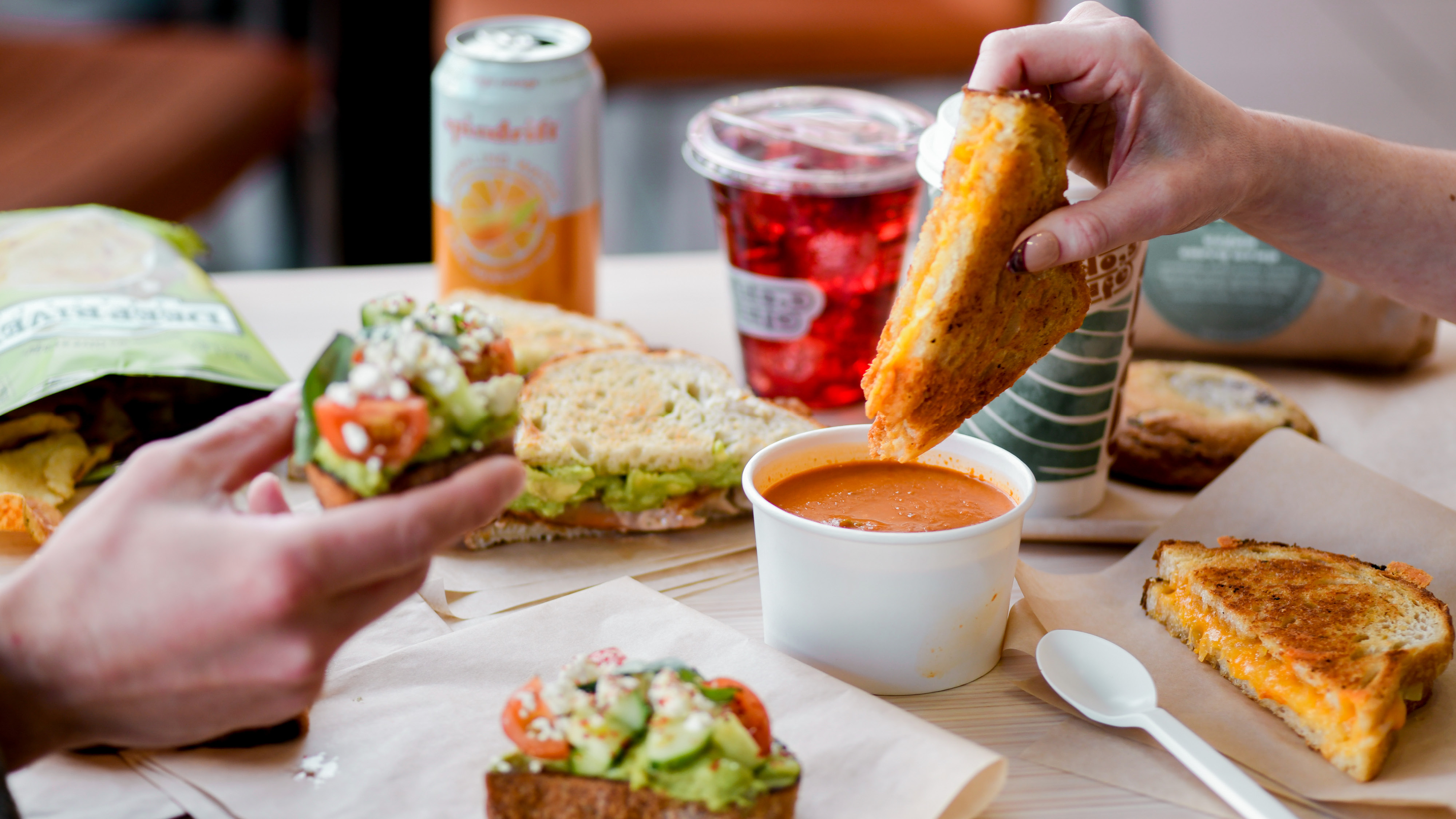 a person holding a plate of food on a table