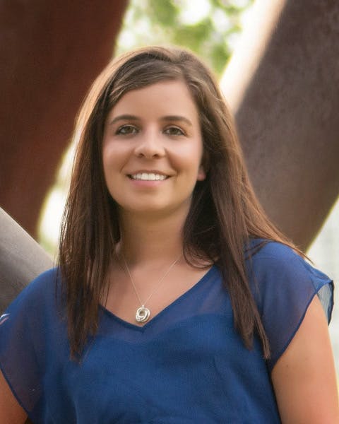 a woman in a blue shirt and smiling at the camera