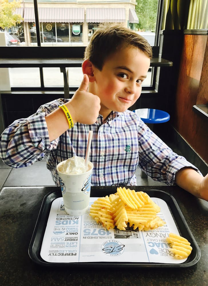 a boy sitting at a table eating food