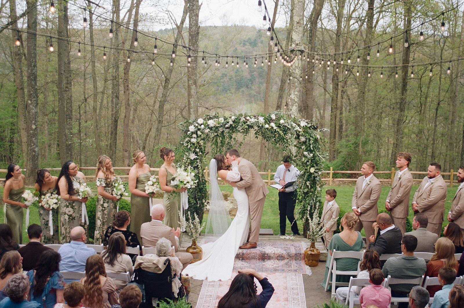 a man and woman kissing under a arch with people in the background