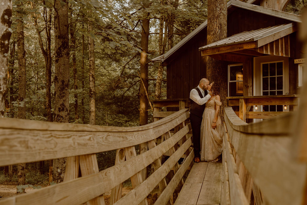a man and woman standing on a bridge in the woods