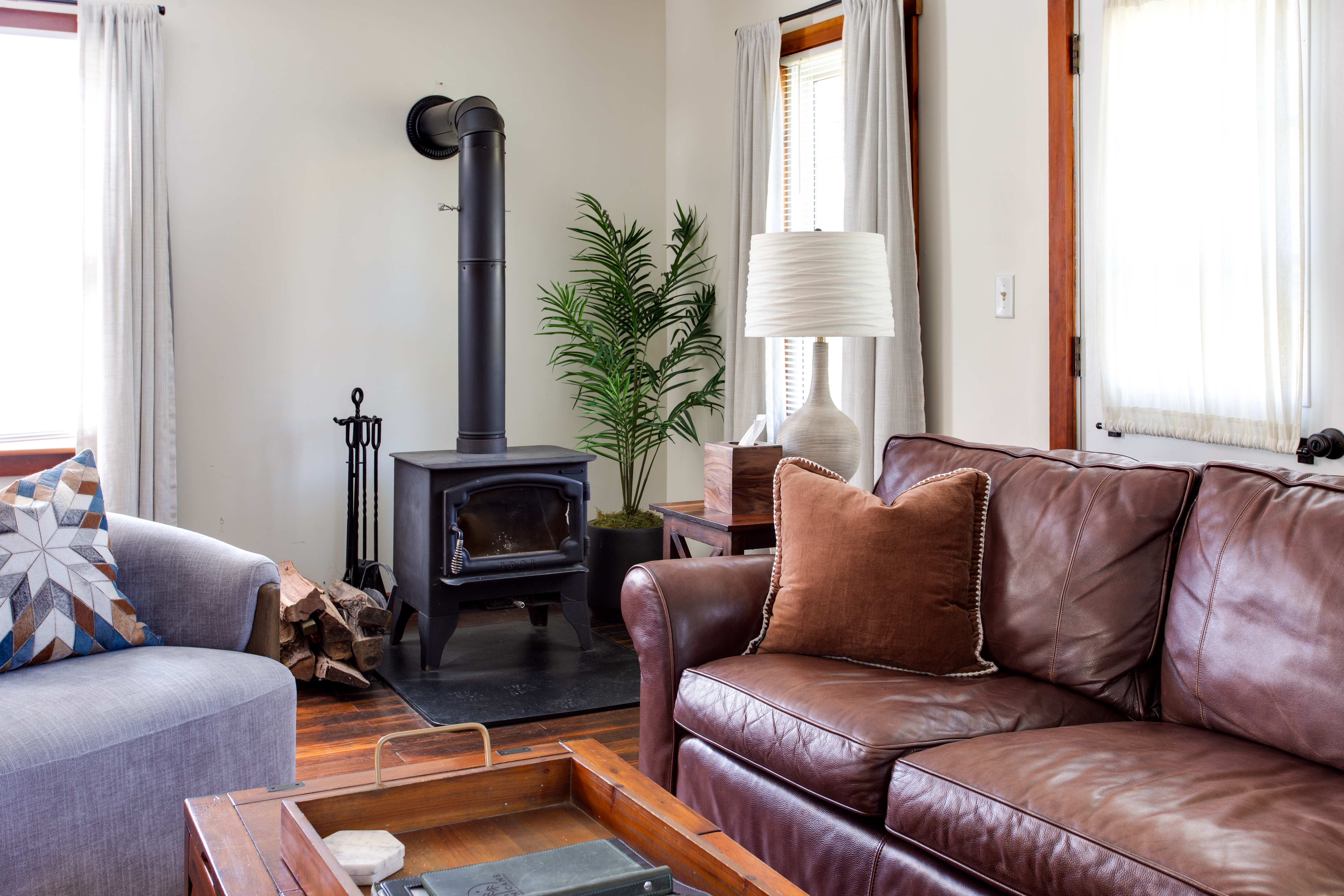 a brown leather couch in a living room filled with furniture and a window