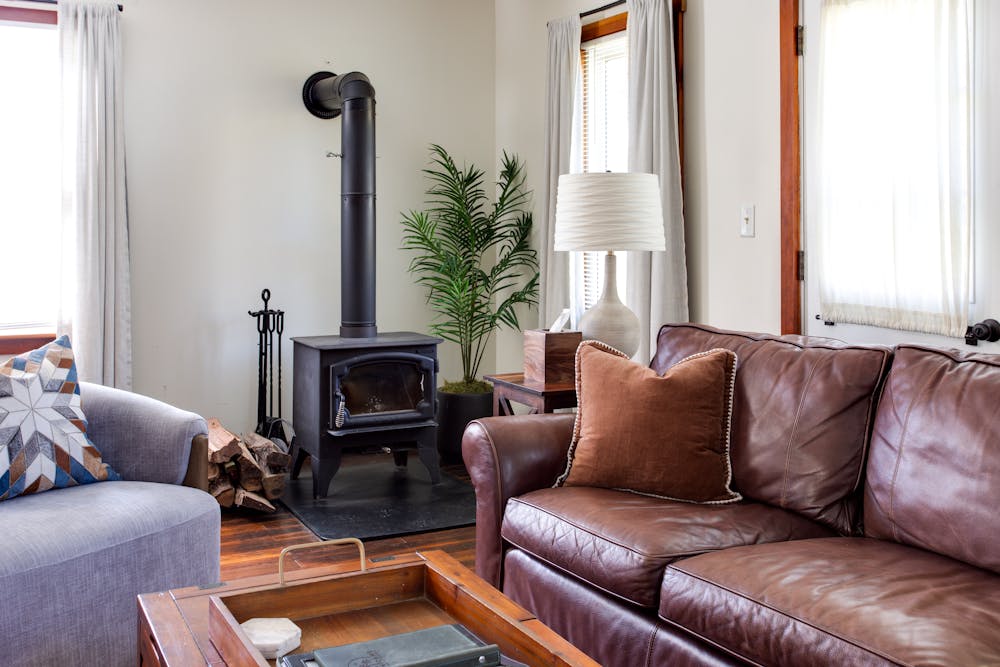 a brown leather couch in a living room filled with furniture and a window