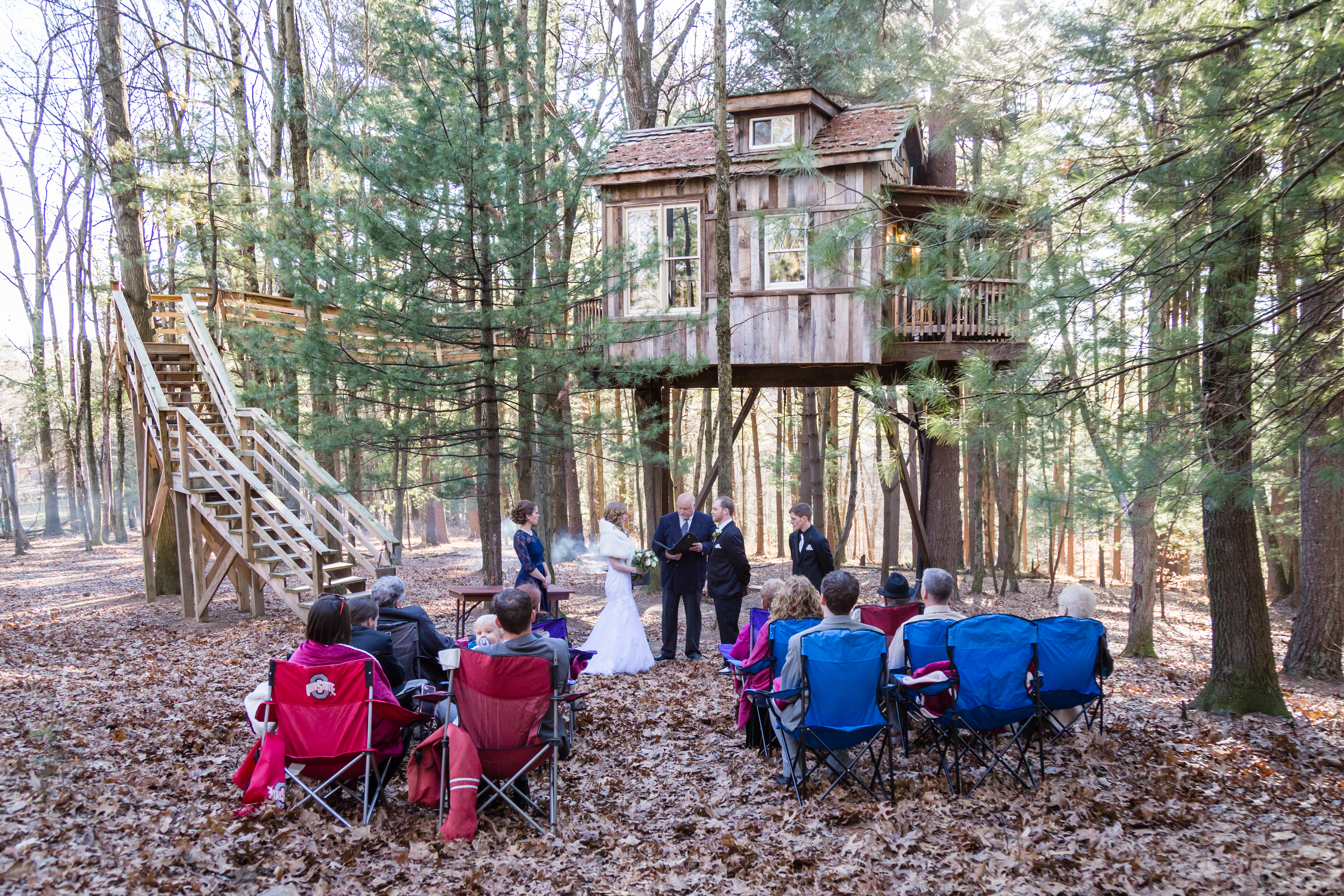 a group of people in chairs in front of a tree house