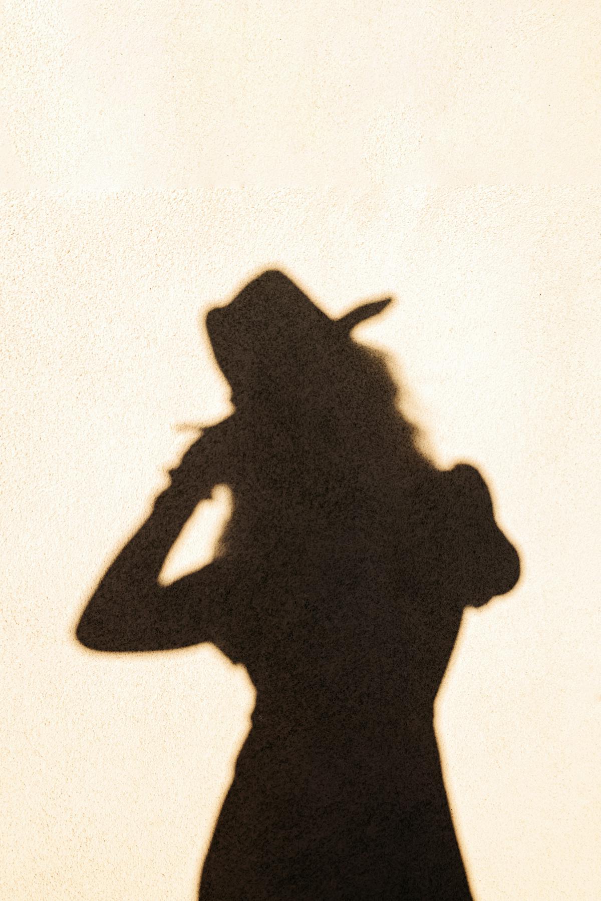 Silhouette of a cowgirl as a shadow on a wall.