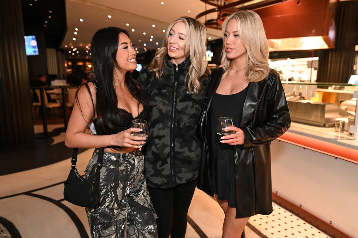 three women standing in a room holding cocktails