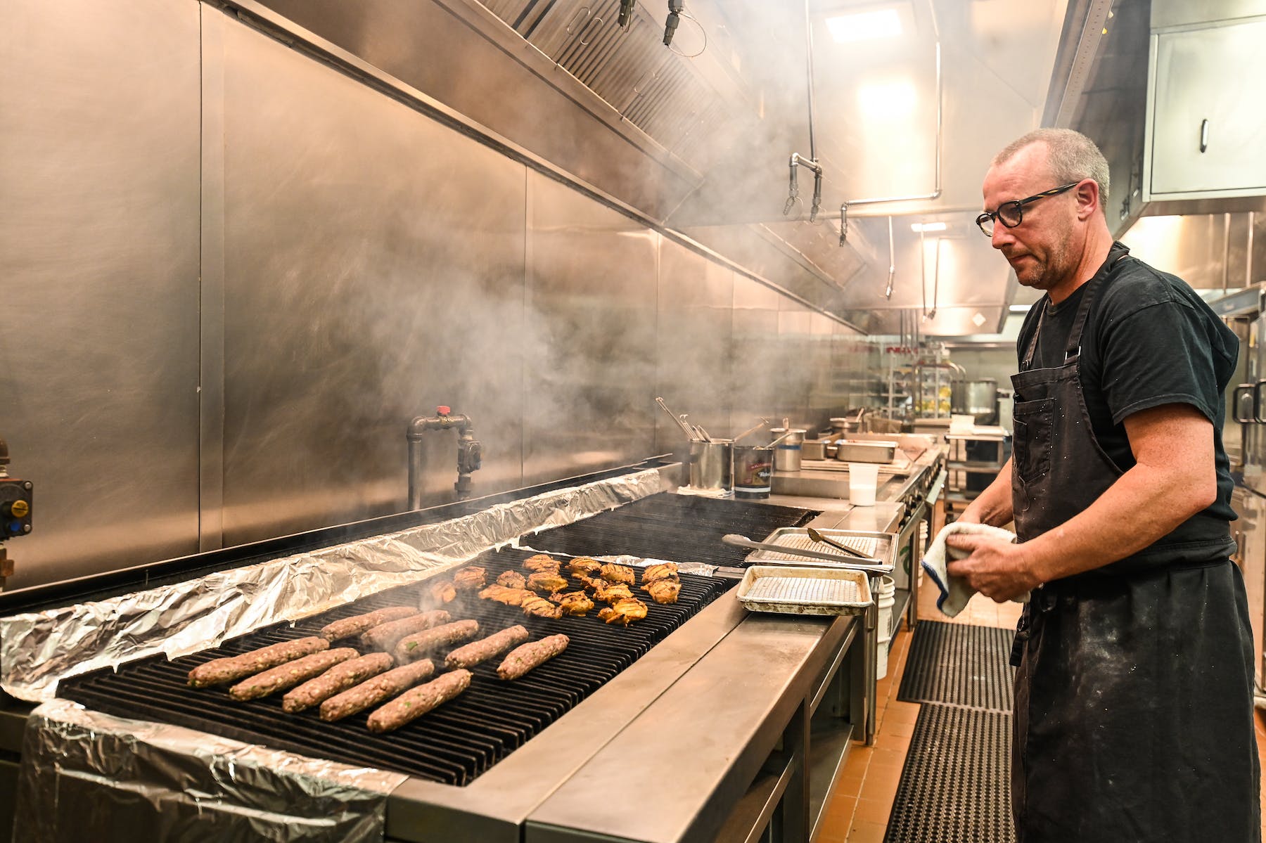 a man cooking hot dogs on a grill