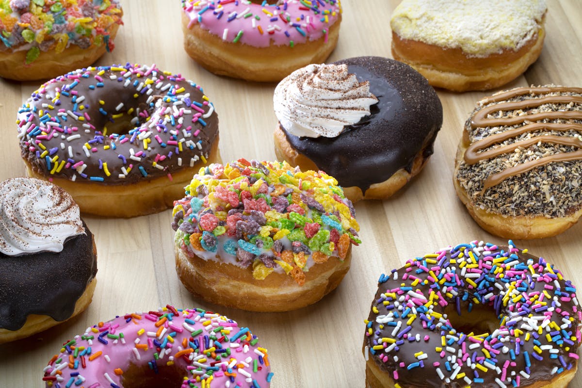a variety of donuts sitting on top of a table covered with different toppings