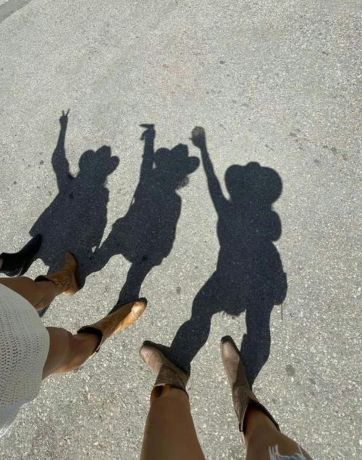 Group of cowgirls in cowboy hats and cowboy boots posing on a sidewalk shadow