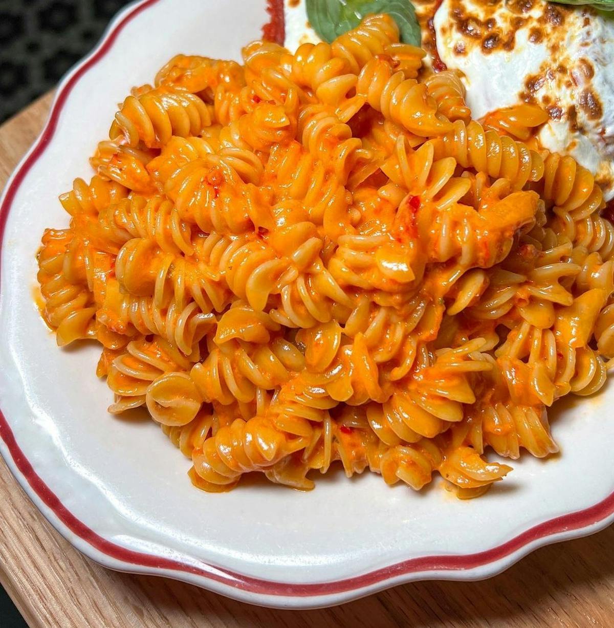 rotini pasta with spicy vodka sauce on a white plate with red borders