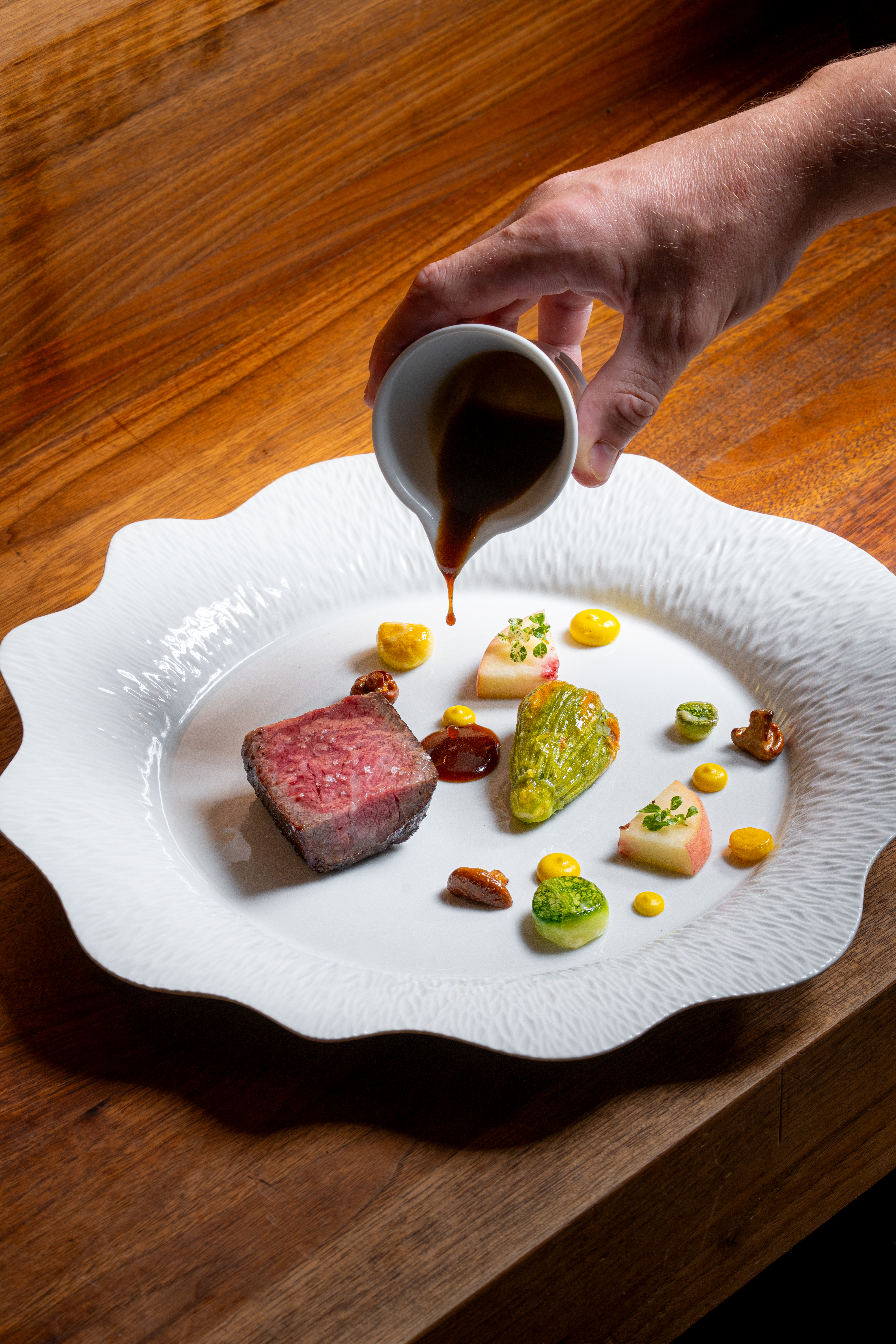 a hand pouring sauce on a plate of food