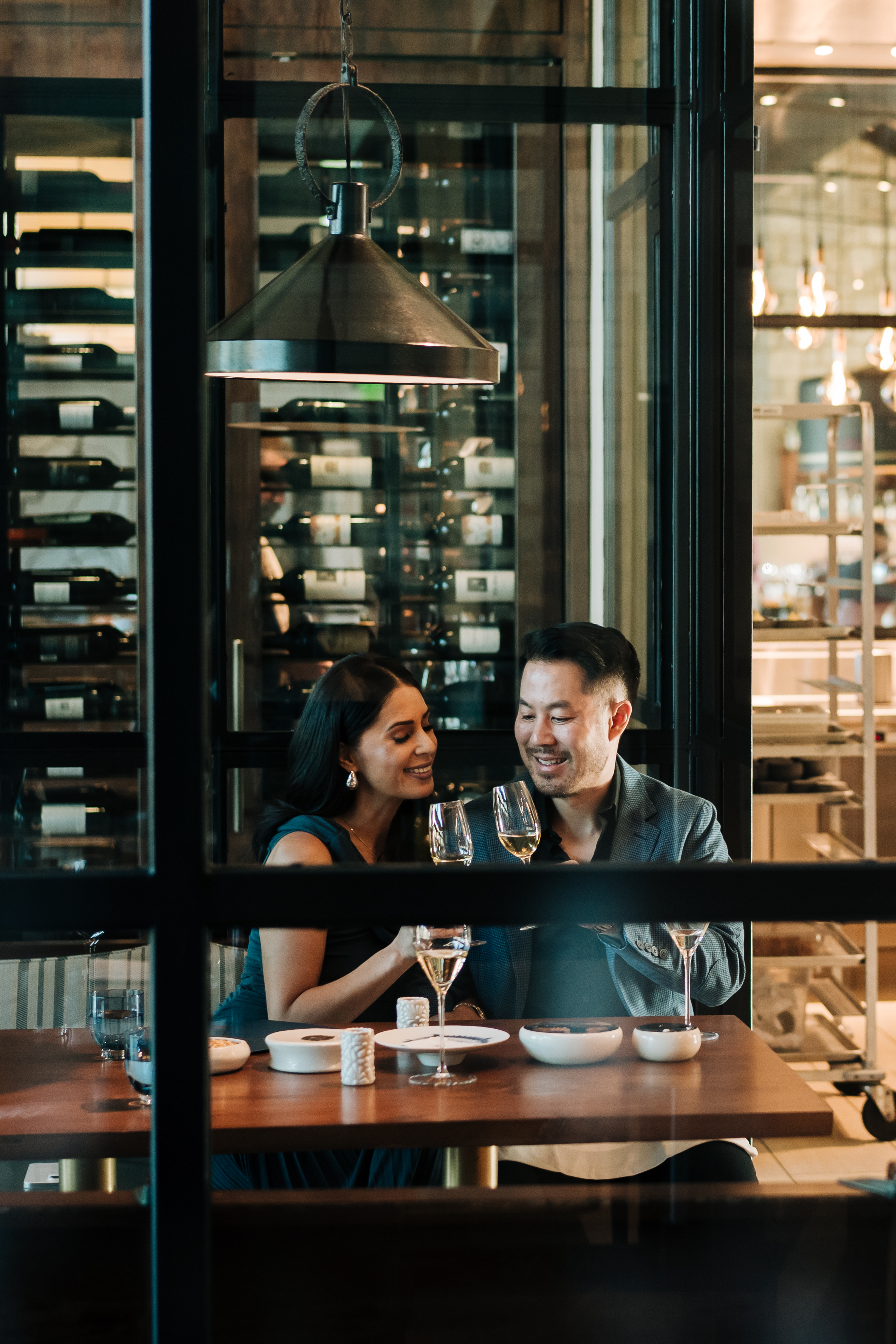 a man and woman sitting at a table with wine glasses