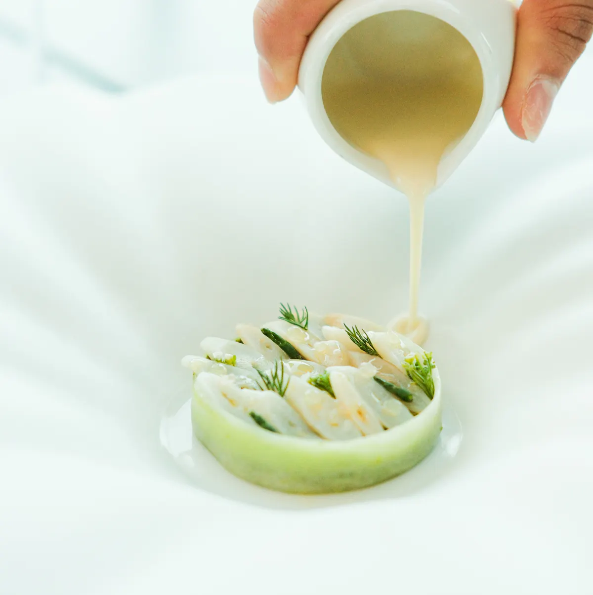 a person pouring sauce onto a food