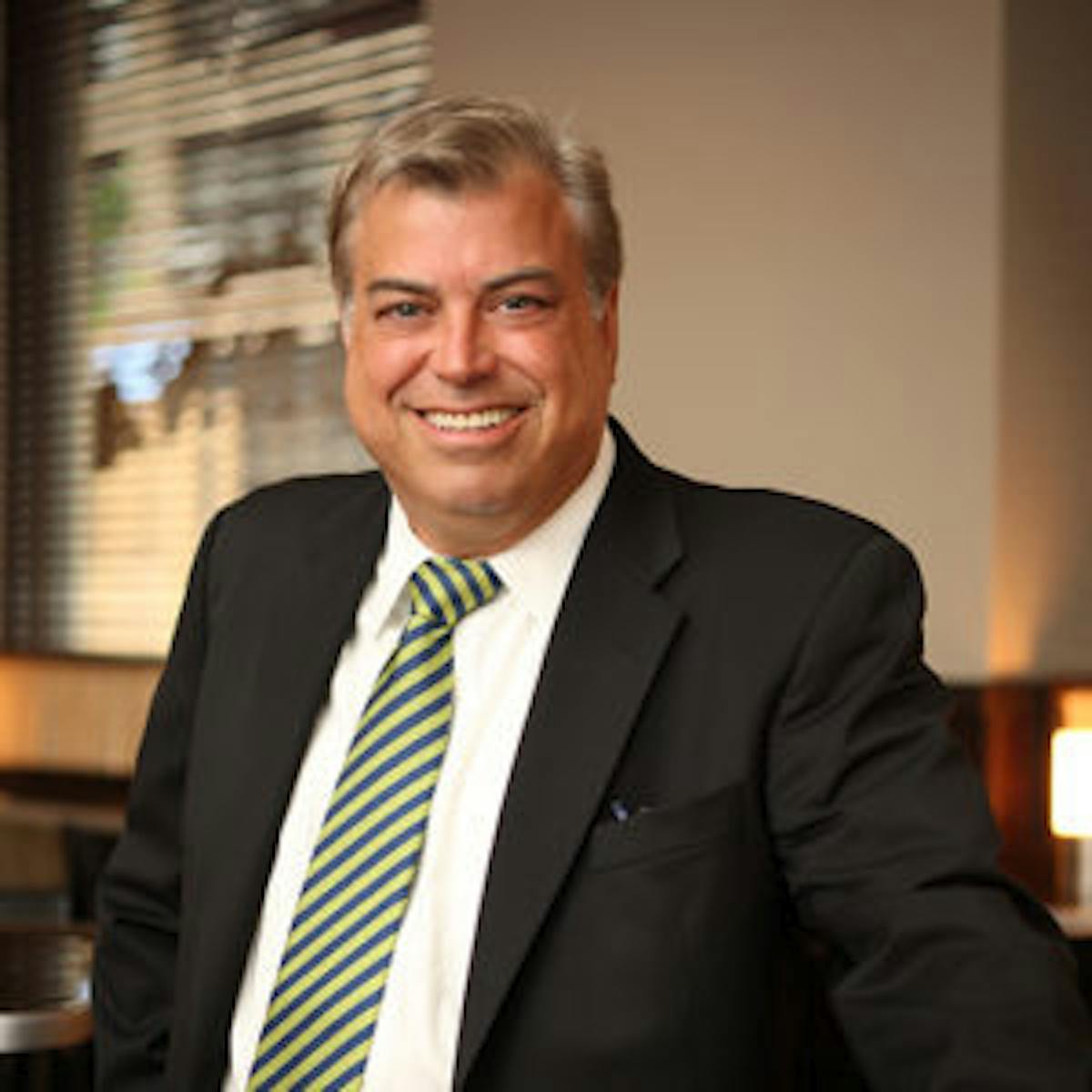 a man wearing a suit and tie smiling at the camera