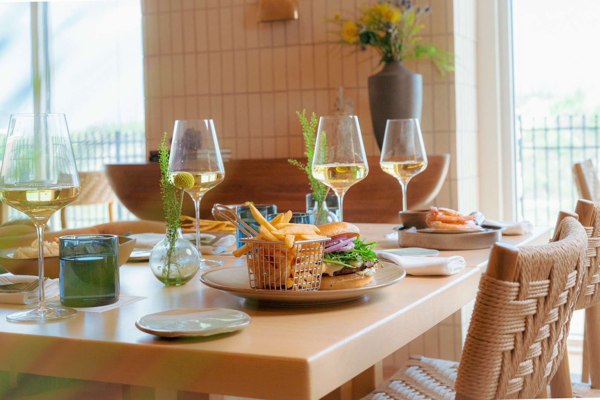 table with white wine glasses and good in airy dining room