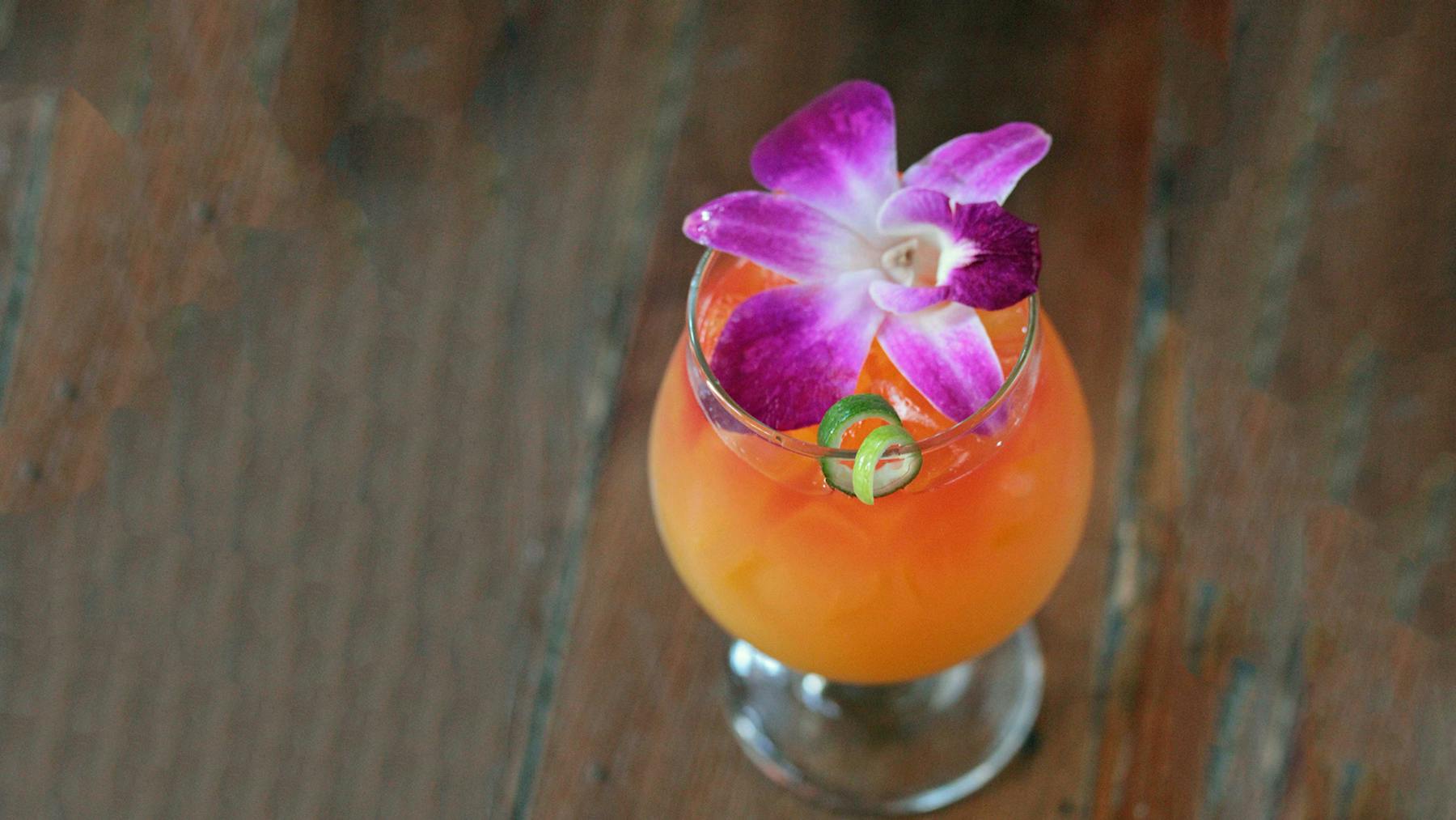 a tropical drink with a flower on top sitting on a table