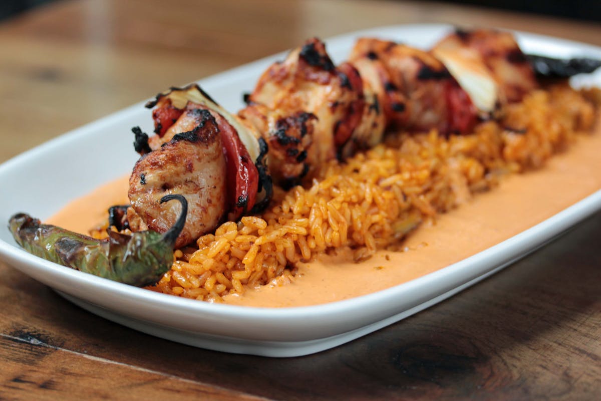 a plate of rice and chicken kabob
