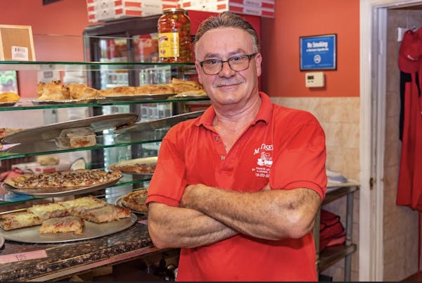 a man standing near pizzas