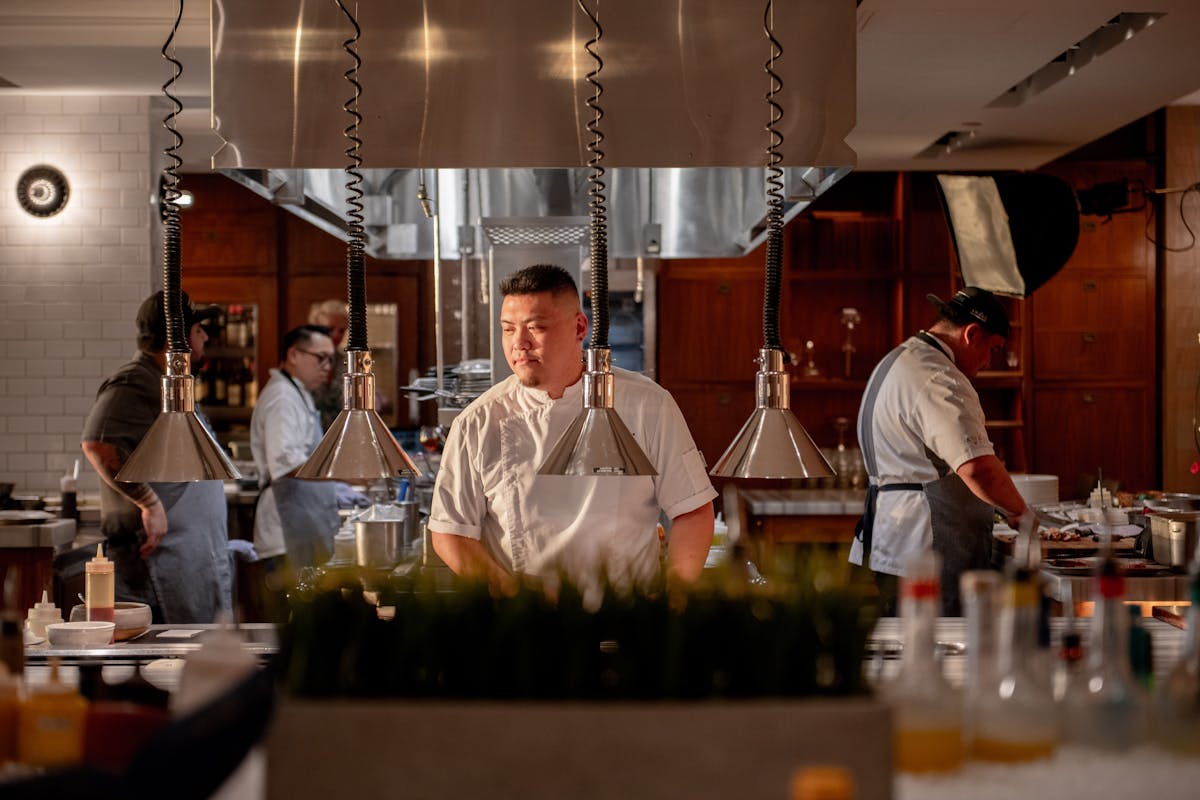 a chef standing in the kitchen looking over the food