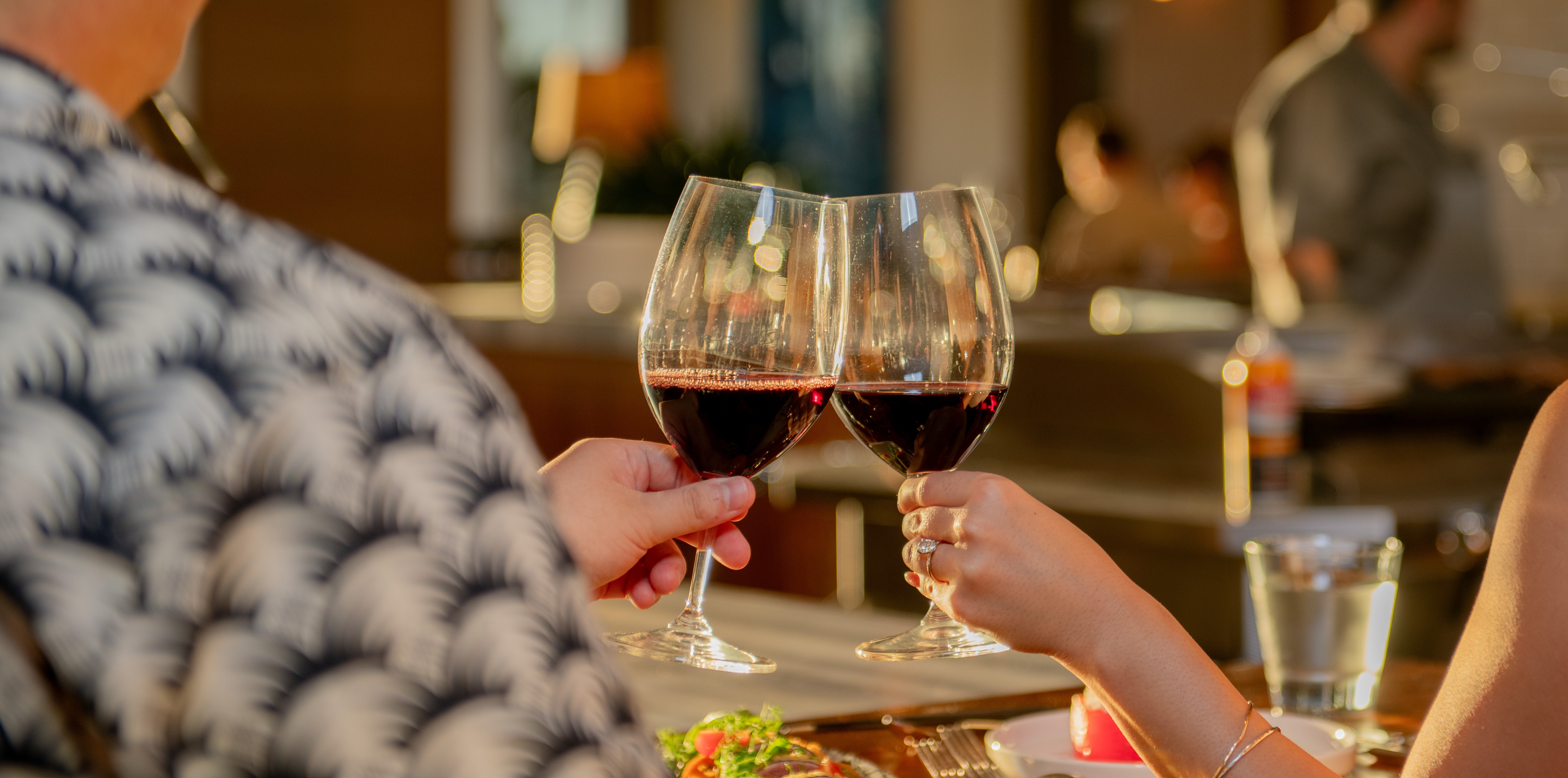 a person sitting at a table with wine glasses