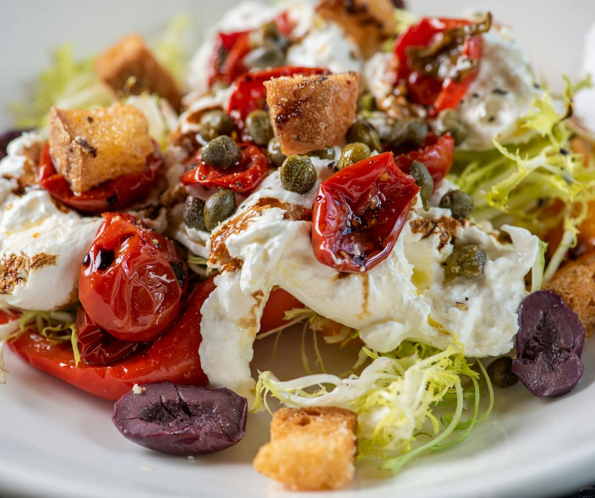 a picutre of a salad with cheese olives and tomatoes