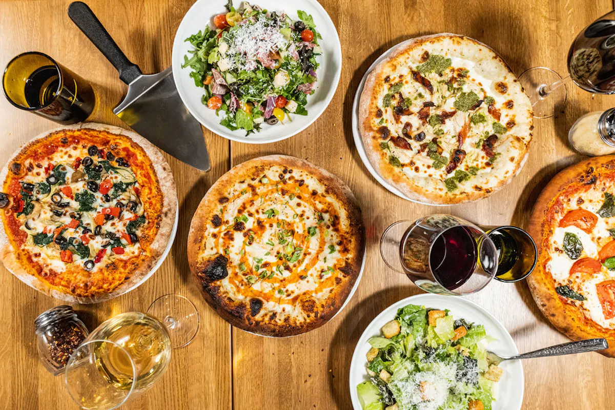 a table with pizzas and salads
