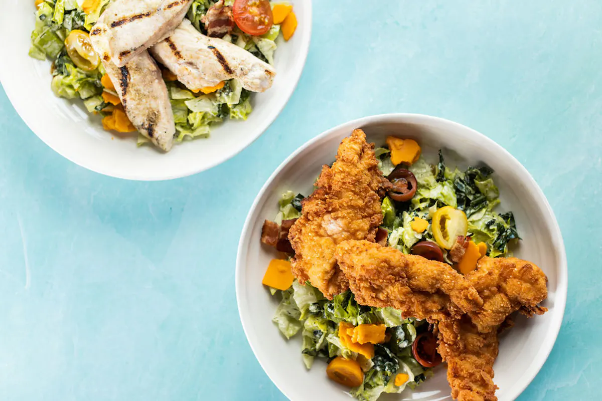 a bowl of salad with chicken strips and vegetables