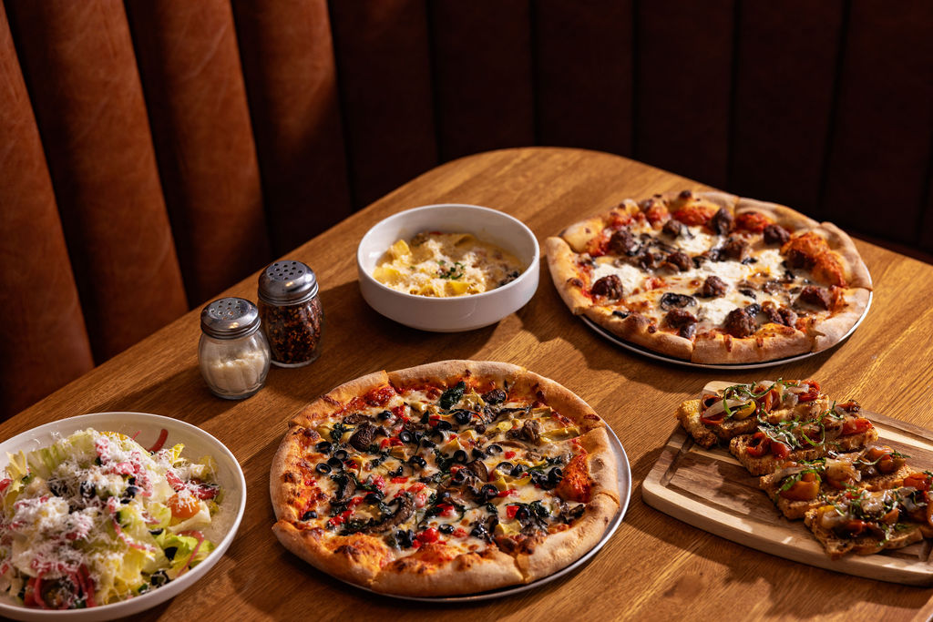 a table with pizzas and salad