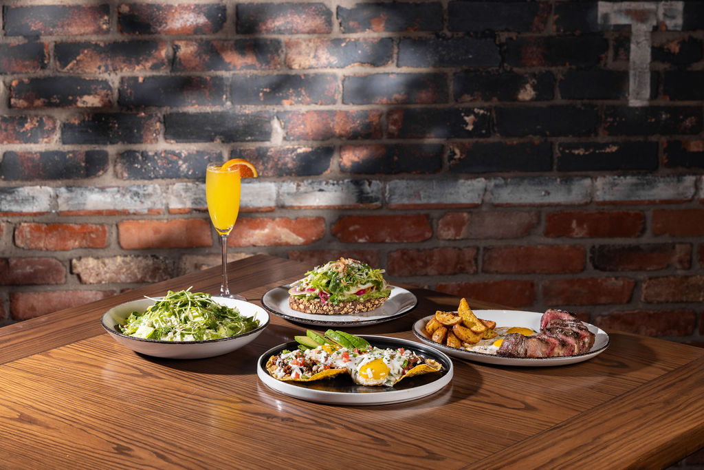 a table with plates of food and a glass of juice