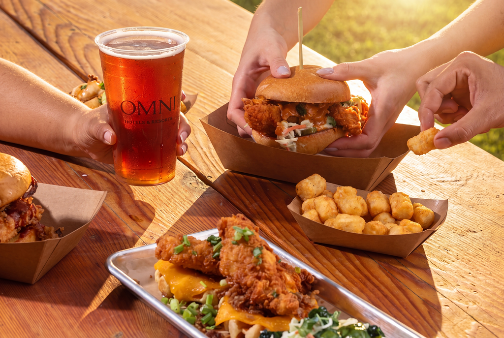 a group of hands holding a burger and a drink