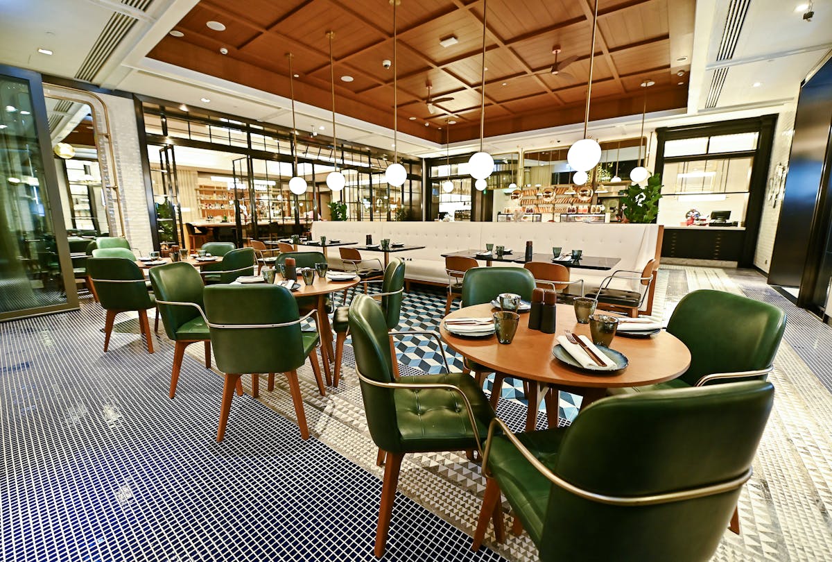 jones social dubai restaurant floor with green chairs and wooden tables