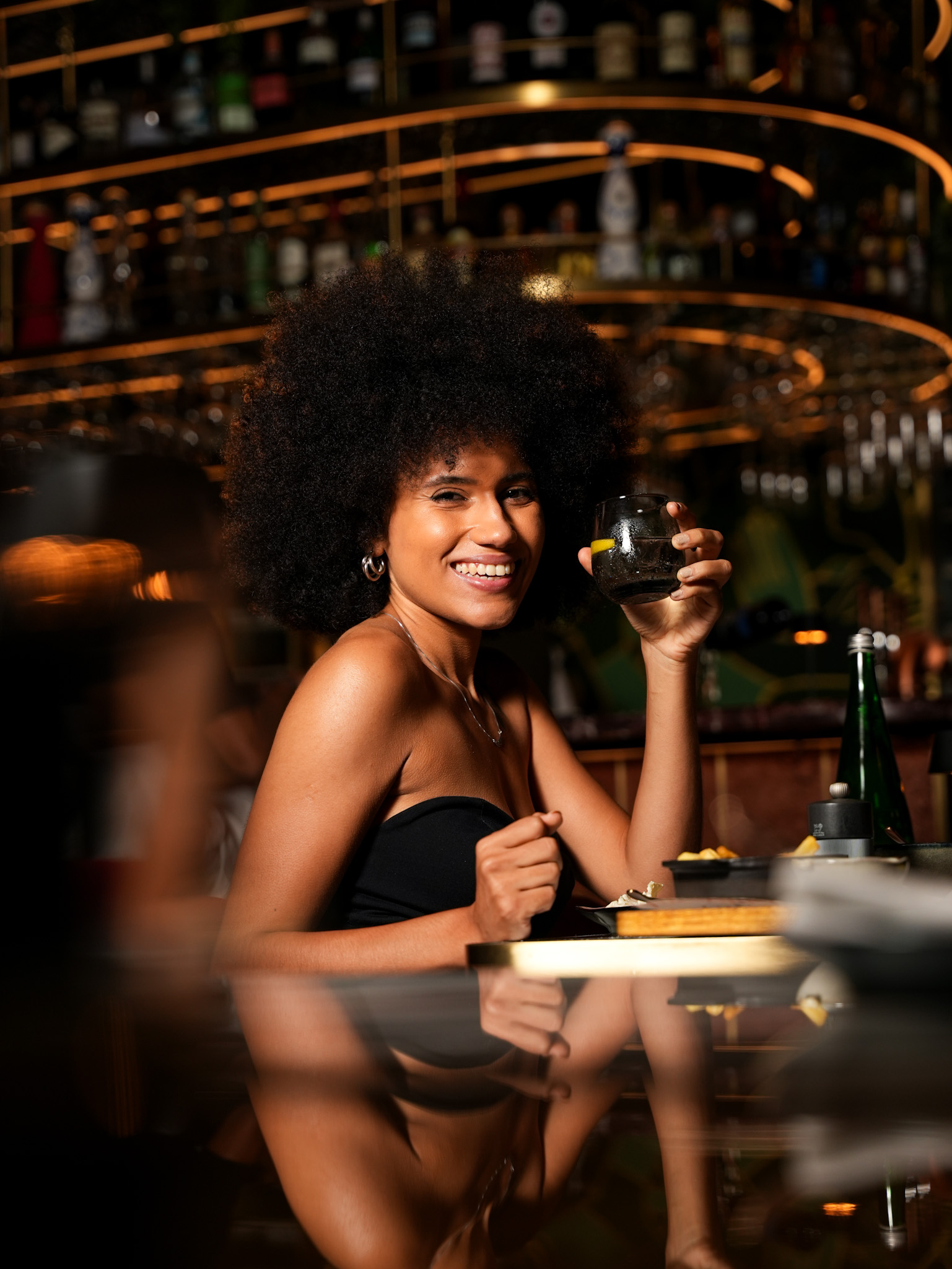 a woman sitting at a table holding a drink