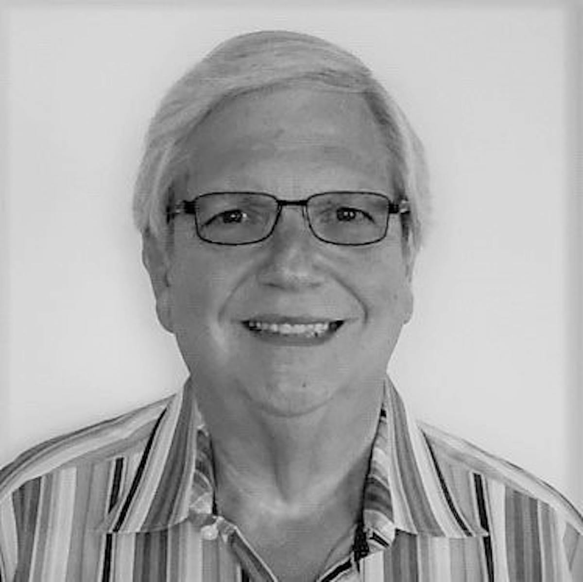 Sy Ginsberg wearing glasses and smiling at the camera
