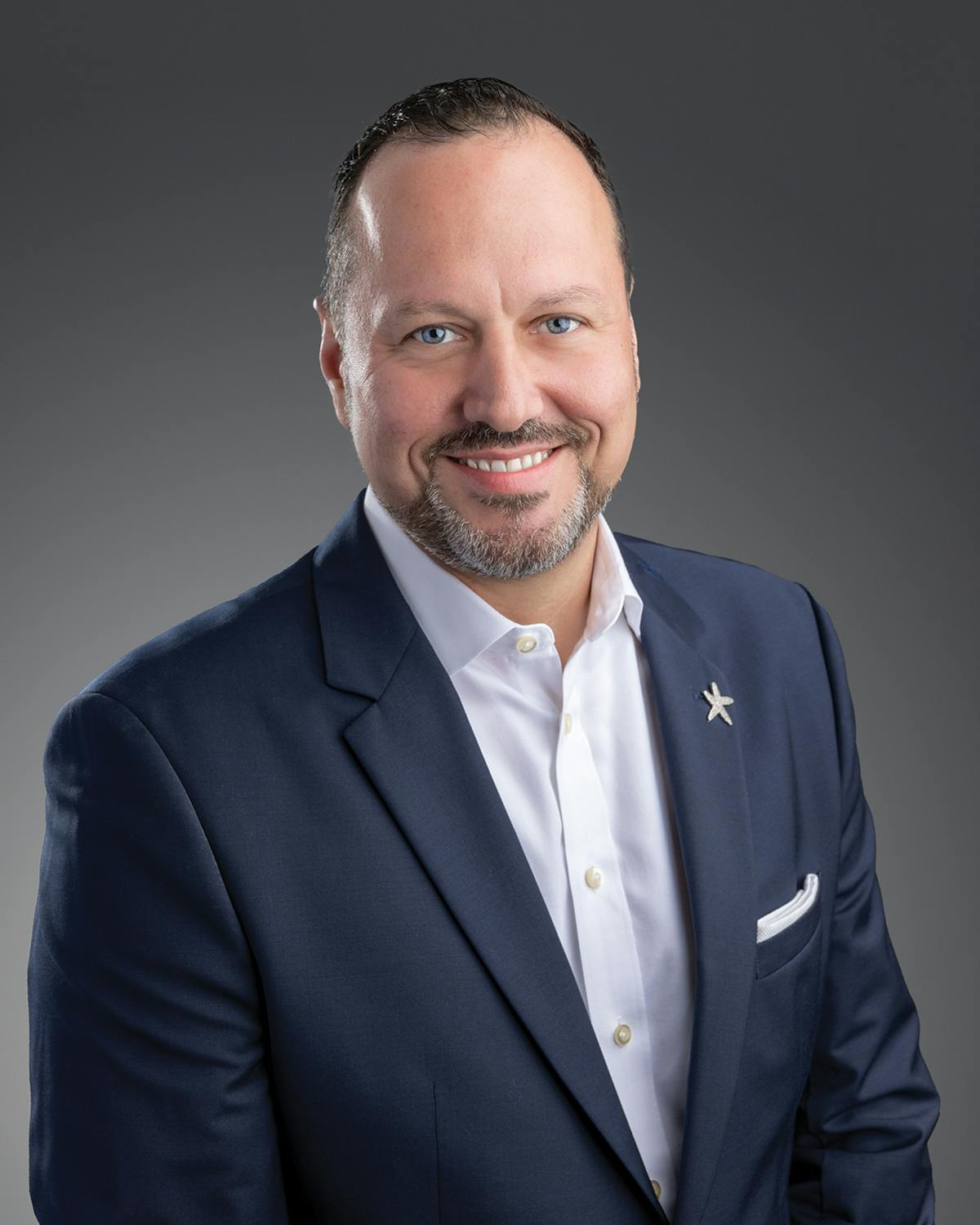 a man wearing a suit and tie smiling at the camera