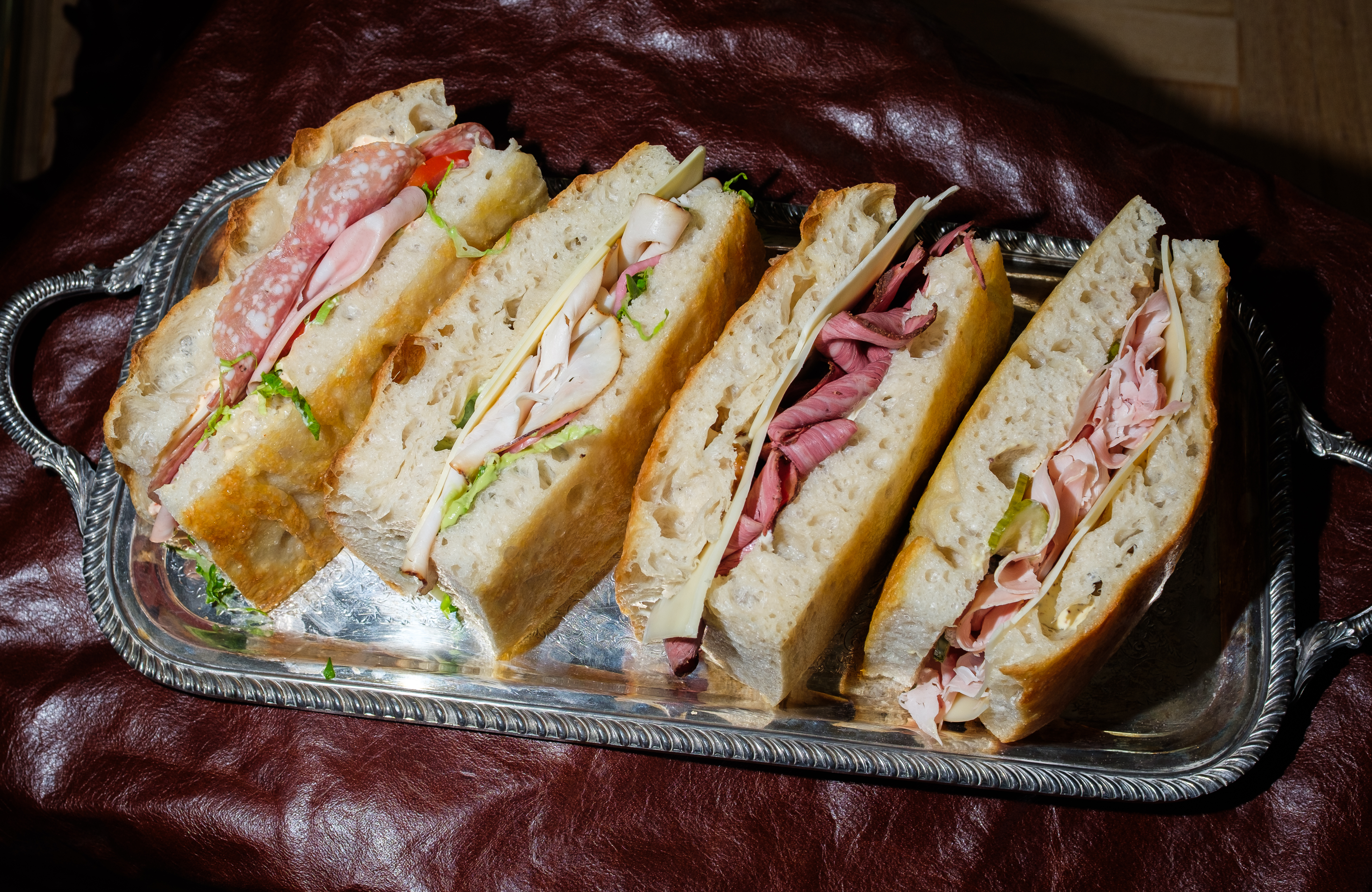 a tray of sandwiches on a leather surface