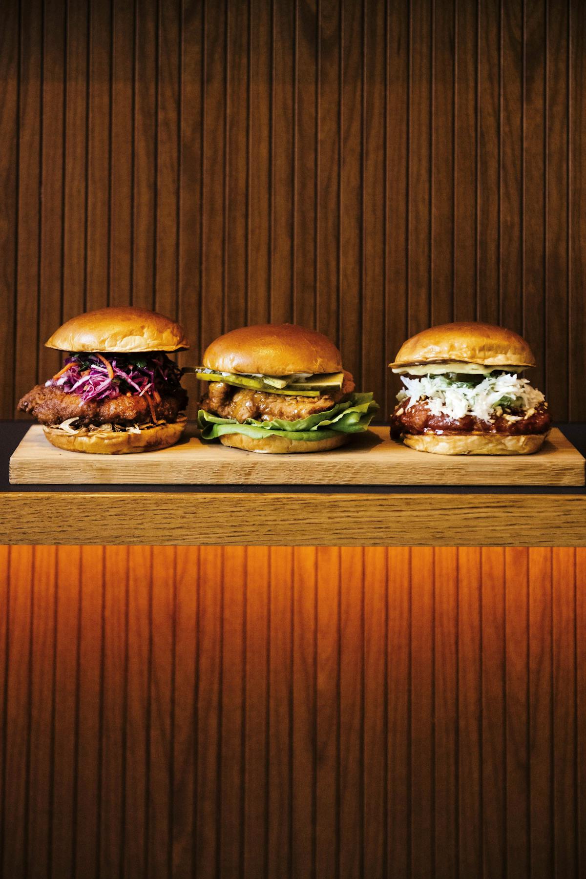 3 chicken sandwiches on a wooden slab