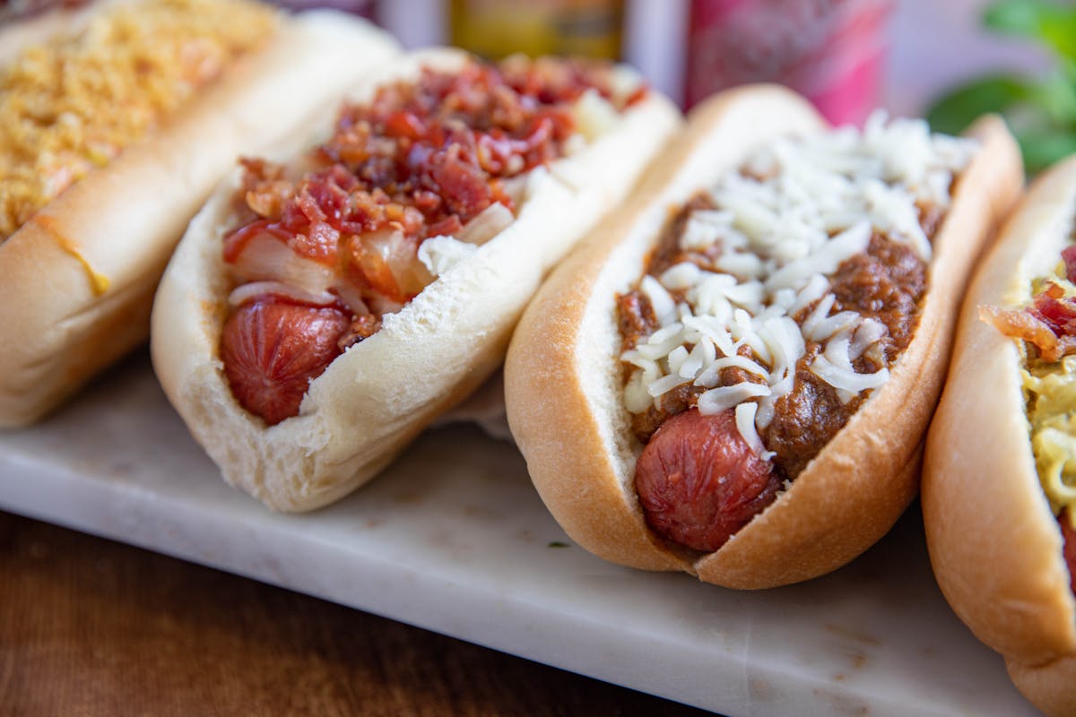 a close up of a lot of hot dogs covered in toppings