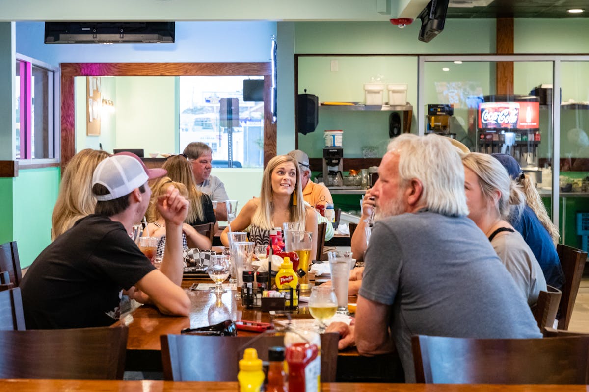 a group of people sitting on a large table at the restaurant