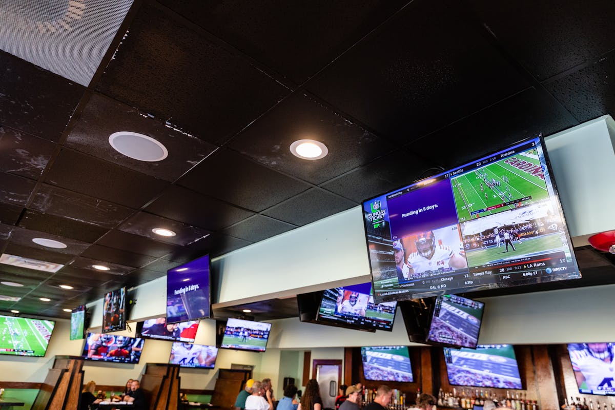 tv screens with football games placed on a wall