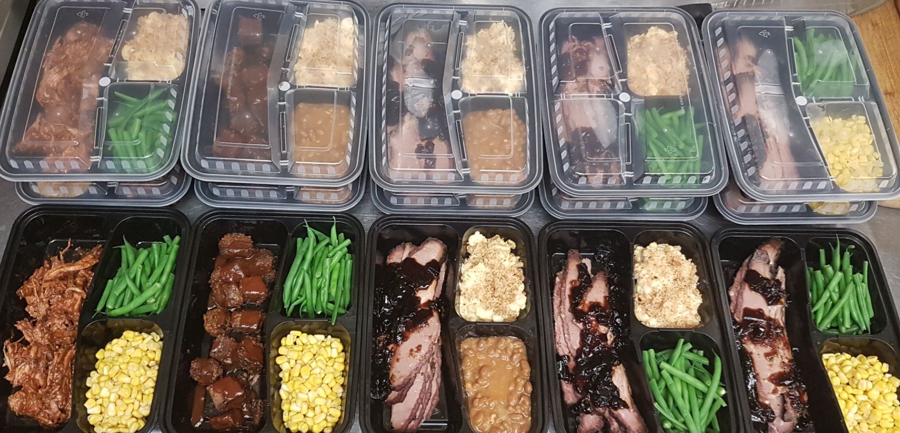 A tray featuring plastic containers filled with meat, beans, and corn, arranged for a meal presentation