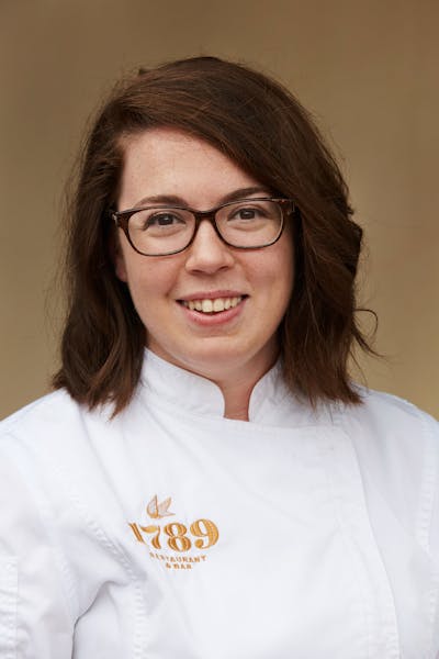 a woman wearing glasses and smiling at the camera